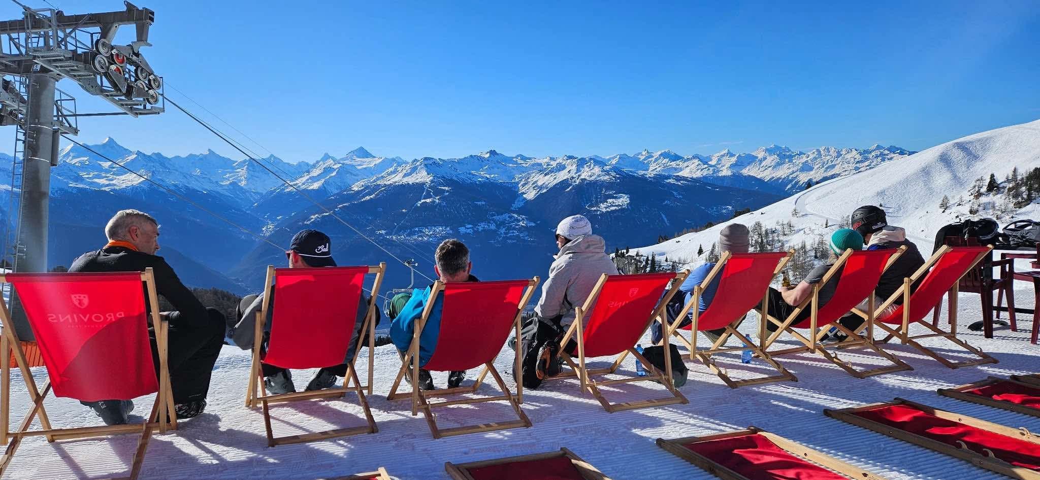 Ski trip view across snowy mountains and red deck chairs