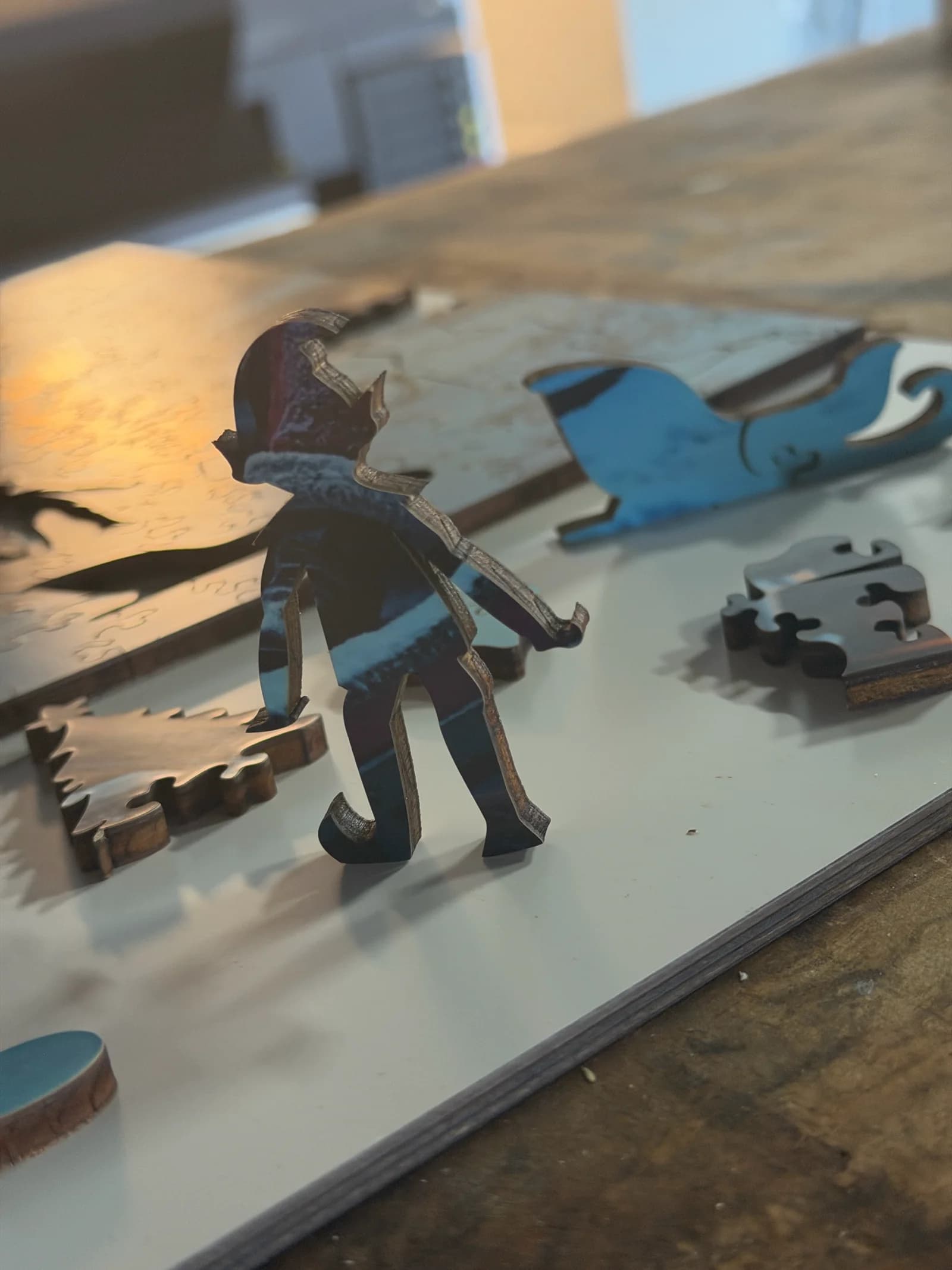 Real Christmas-themed story pieces standing on a hardwood Whittled puzzle