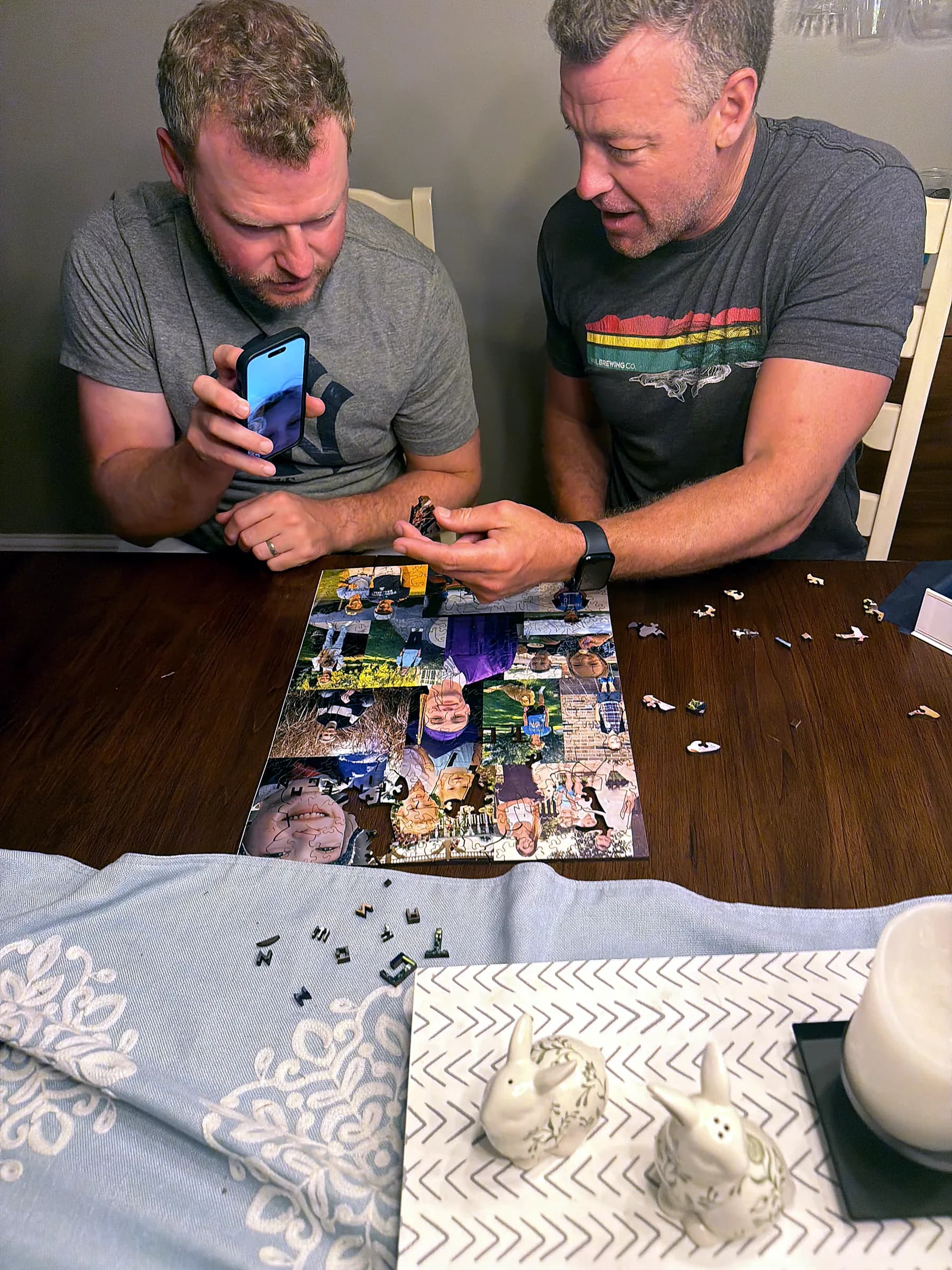 Loose whimsy and letter-shaped puzzle pieces on a table beside a collage puzzle in progress