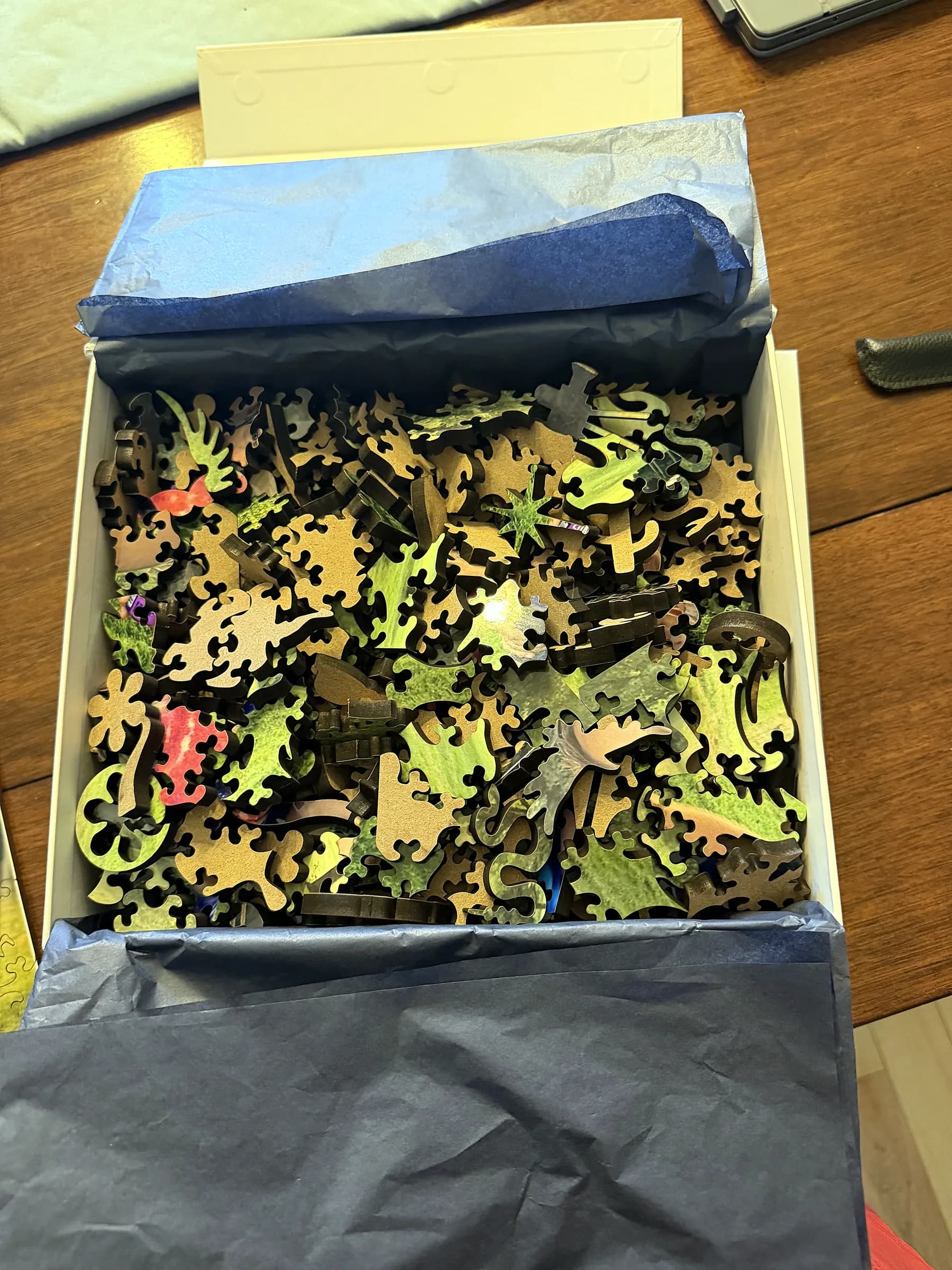 Open Whittled box with navy tissue and hardwood puzzle pieces inside