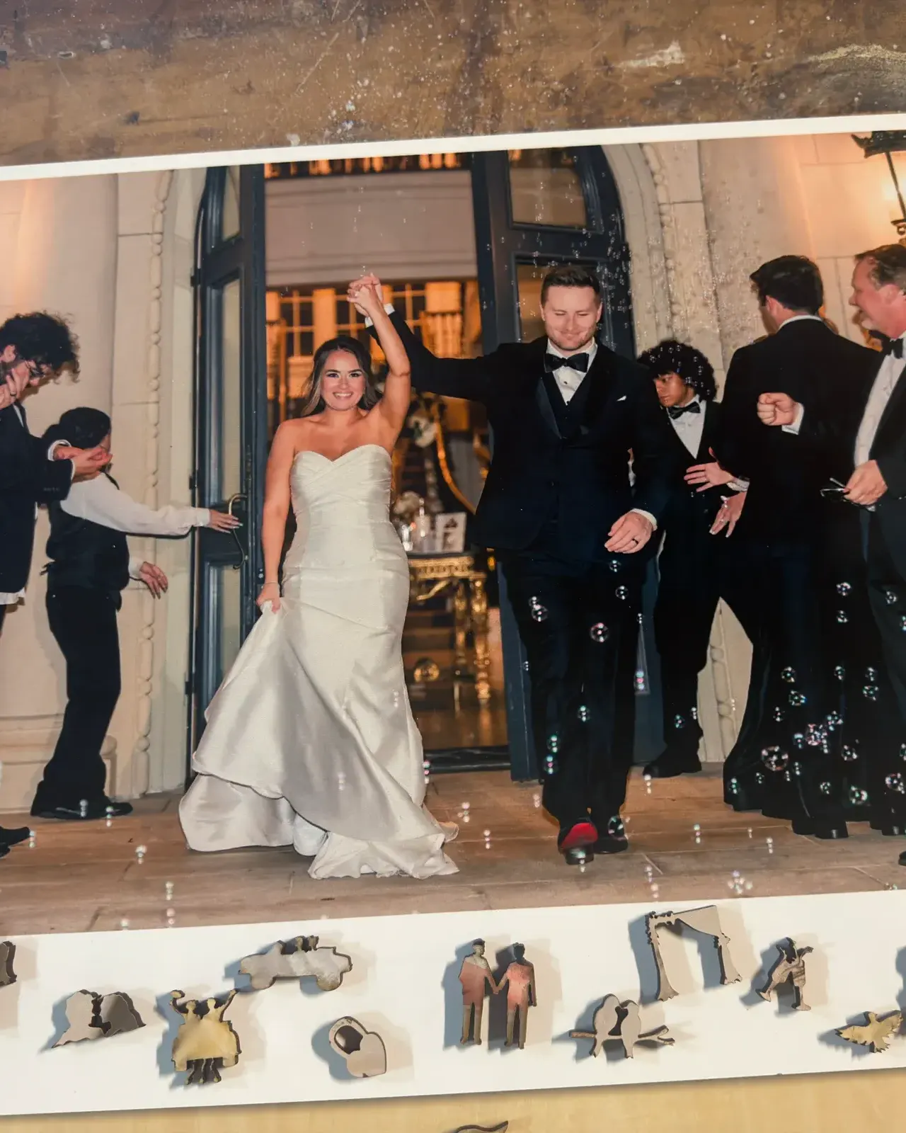 A real wedding photograph on hardwood with wedding-shaped pieces arranged below it